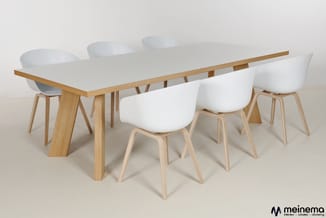 Witte vergadertafel met houten frame en blad, omgeven door vier witte stoelen met houten poten. Meinema-logo onderaan rechts.