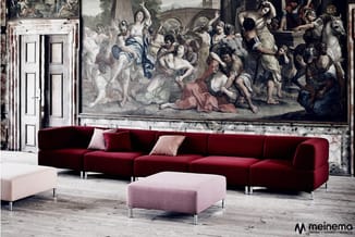 Rode modulaire bank met chaise longue en roze poefs in klassieke zaal met fresco aan wand en witte deuren.