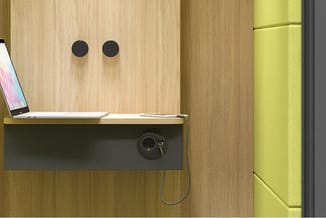 Werkplek met houten wandpanelen, ingebouwde bureau met zwarte voorkant, laptop, zwarte ronde handgrepen en elektrisch stopcon