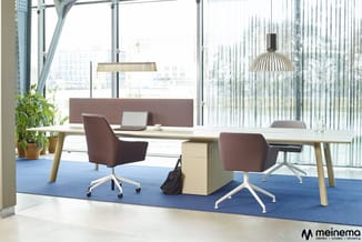 Modern kantoor met twee lichte houten bureaus op blauw tapijt, bruine stoelen met wielen, houten kastje, hangende design lamp