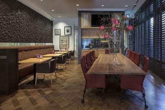 Moderne vergaderruimte met houten vergadertafel, bordeauxrode stoelen op wielen, bruine zitbanken, textured muurafwerking en