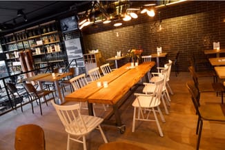 Moderne kantoorruimte met lange houten vergadertafel, witte stoelen, bakstenen muur, boekenkasten, hangende verlichting en ho