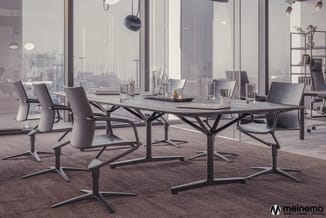 Moderne vergadertafel met zwart onderstel en grijze blad, omgeven door grijze vergaderstoelen, in hooggelegen kantoor met pan