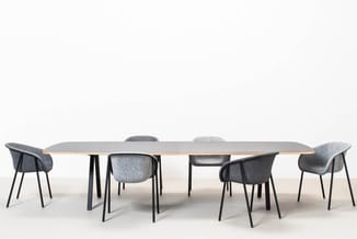 Vergadertafel met licht blad en zwarte poten, omringd door zes grijze stoelen met zwart metalen frame, op witte achtergrond.