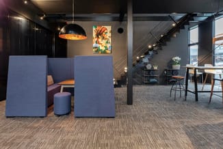Moderne kantoorruimte met blauwe akoestische panelen, zwarte hanglamp, grijze vloerbedekking, trap en vergadertafel met houte