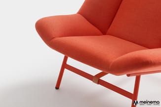 Rode lounge stoel met gewatteerde zitting en rugleuning, rode metalen pootjes, tegen witte achtergrond.