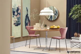 Ronde eettafel met houten blad en roestvrij stalen poot, twee roze fluwelen stoelen, hanglamp, wandspiegel, kunstwerken, plan