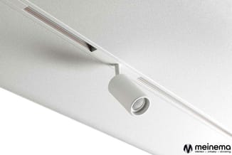 Witte railverlichting aan plafond met cilindervormige spotlight en ingebouwde elektriciteitsdraad.