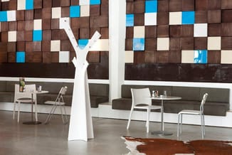 Moderne kantoorruimte met grijze zitbanken, witte stoelen, tafels en een wit sculptuurobject. Achterwand met bruine en blauwe