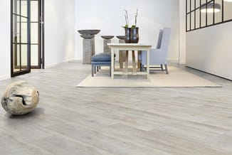 Moderne eetkamer met lichte houten tafel, grijsblauwe stoel, decoratieve vazen, stenen objecten en grote ramen in minimalisti