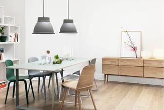 Modern kantoor met witte eettafel, houten stoelen, groene stoel, grijze hanglampjes, houten dressoir, witte wandkasten en hou