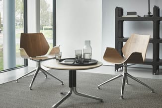 Moderne vergaderruimte met rond tafelblad en twee houten draaistoelen met chromen poten rond een centrale tafel. Grote ramen,