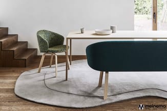 Moderne kantoorinrichting met houten tafel, grijze ovale vloerkleed, groene stoel en donkerblauwe fauteuil. Meinema-logo onde
