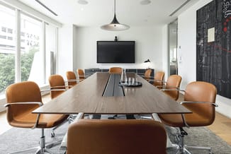 Moderne vergaderruimte met lange houten tafel, bruinleren draaistoelen, zwart TV-scherm aan wand, hanglamp, glazen wand, grot