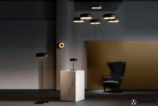 Verlichte showroom met zwarte hanglampen, witte marmeren zuil, zwarte vloerlamp, goudkleurige wandlamp, en zwarte fauteuil te