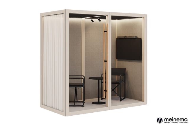 Moderne belcel met beige frame en grijze binnenwanden, voorzien van zwart bureau, stoel, zwarte monitor en verlichting.