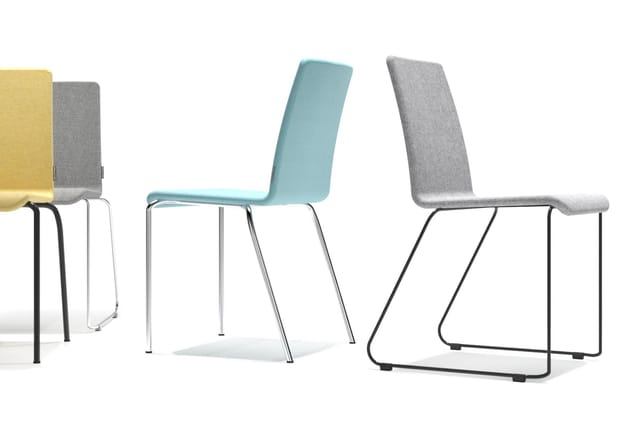 Vier stapelstoelen in verschillende kleuren: geel, grijs, turquoise en grijs, met metalen frames in zilver en zwart.