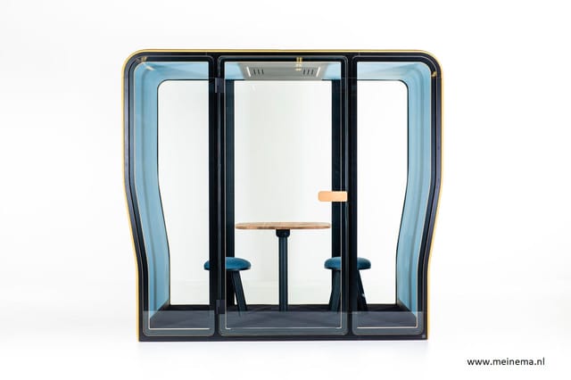 Akoestische telefooncel met zwart frame, blauwe zijpanelen, werkblad en twee blauwe stoelen, openslaande deur met houten hand