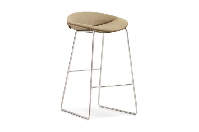 Barkruk met beige gewatteerde zitting en chromen metalen frame met voetsteun, tegen witte achtergrond.