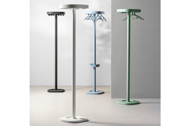 Vijf staande infraroodverwarmers in verschillende kleuren (zwart, grijs, blauw, groen) met platte voetplaten, opgesteld in ee