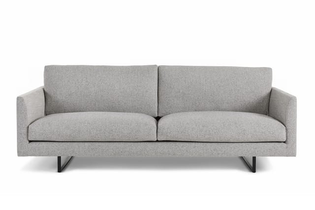 Grijze stof designbank met twee zitplaatsen, armleuningen en zwarte metalen poten op witte achtergrond.