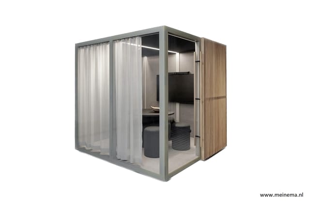 Grijze belcel met glazen deur, witte gordijnen, houten latten zijwand, grijze stoelen en tafel binnen.