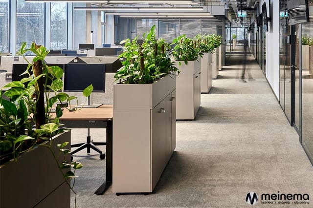 Modern kantoorinterieur met beige kastenconfiguraties met plantenbakken, werkplekken met monitoren en zwarte stoelen langs ee