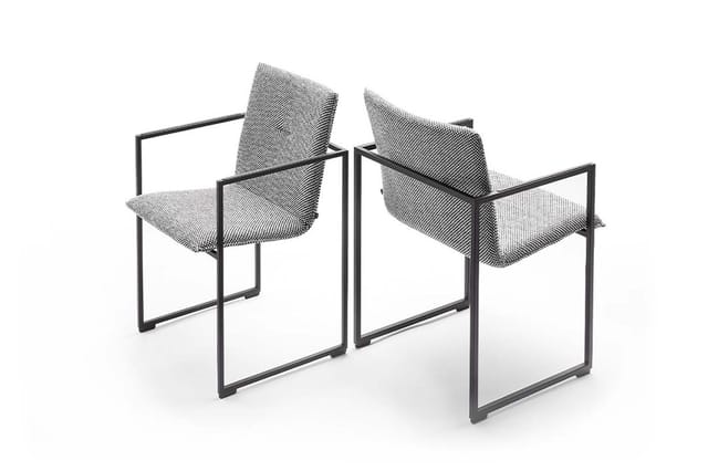 Twee moderne stoelen met zwart metalen frame en grijze mesh-bekleding, gepositioneerd tegenover elkaar.