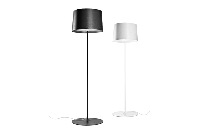 Twee staande lampen met cylindrische kapjes: één zwart met zwart voetje, één wit met wit voetje, beide tegen witte achtergron